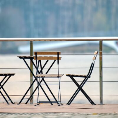 Na dachu tarasu stoją krzesła i stolik złożony ze składanymi nogami do stołu.
