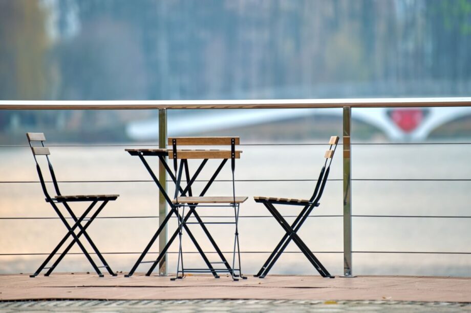 Na dachu tarasu stoją krzesła i stolik złożony ze składanymi nogami do stołu.