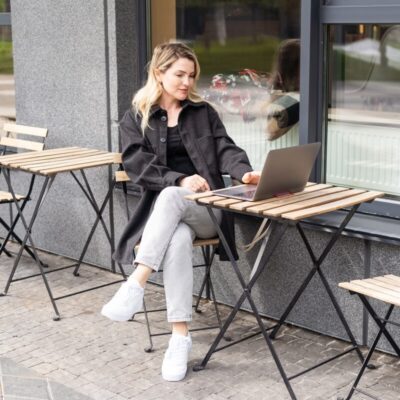 Kobieta siedzi przy stoliku na zewnątrz, który wspierają składane stelaże do stołu.