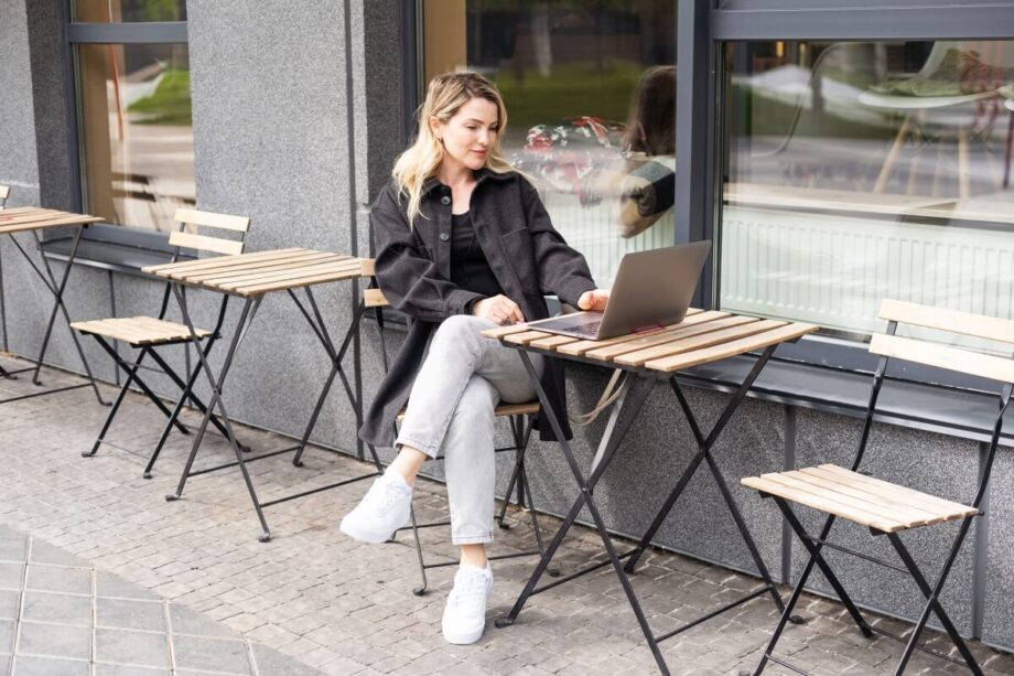 Kobieta siedzi przy stoliku na zewnątrz, który wspierają składane stelaże do stołu.