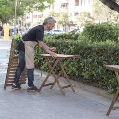 Mężczyzna ustawia stolik w ogrodzie, który ma składane nogi do stołu.