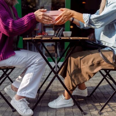 Dwie osoby siedzą przy stoliku z krzesłami, który ma składane nogi do stołu.