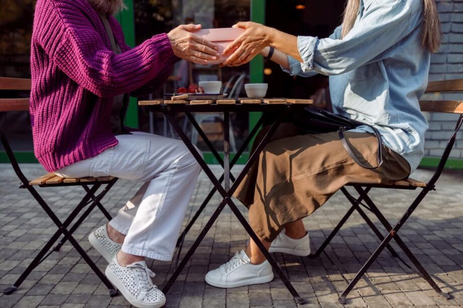 Dwie osoby siedzą przy stoliku z krzesłami, który ma składane nogi do stołu.