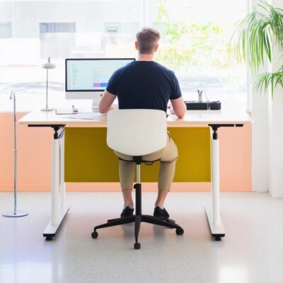 Mężczyzna pracuje przy biurku opartym na stelazach regulowanych.