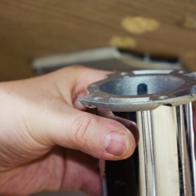 Ręka trzyma element wchodzący w skład stelazy metalowe do stołu.