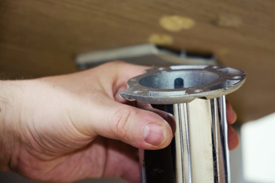 Ręka trzyma element wchodzący w skład stelazy metalowe do stołu.