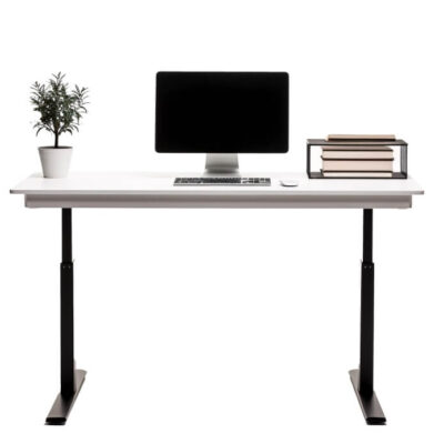 Biurko z komputerem i książkami stoi na stelazach regulowanych mechanicznie.