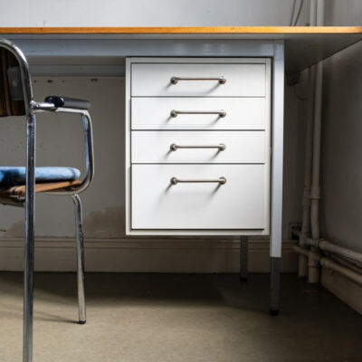 Biurko z białymi szufladami biurowymi i metalowym krzesłem obok.