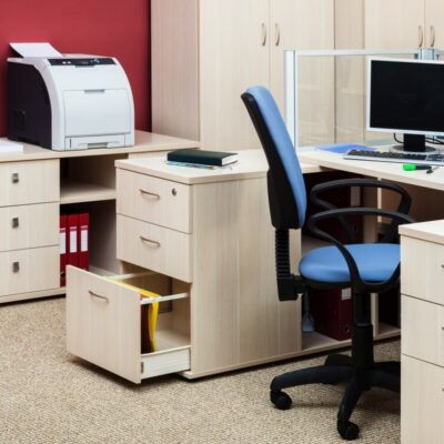 Biuro z komputerem, drukarką i otwartymi szufladami biurowymi pełnymi dokumentów.